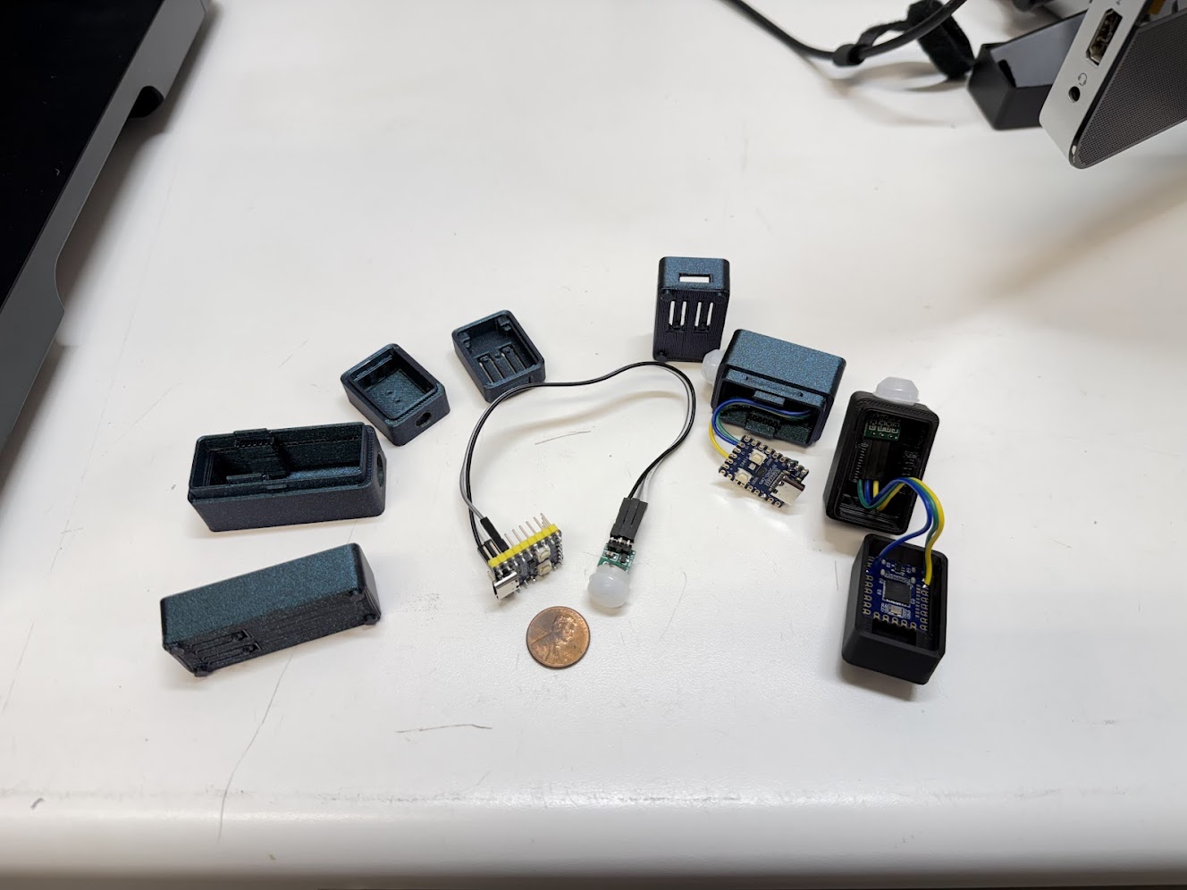 Multiple 3D-printed MOTIONSENSR enclosure iterations in different sizes laid out on a white surface